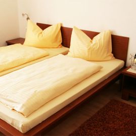 Hotelbett mit gelber Bettwäsche in einem Hotel mit WLAN im Bezirk Weiz